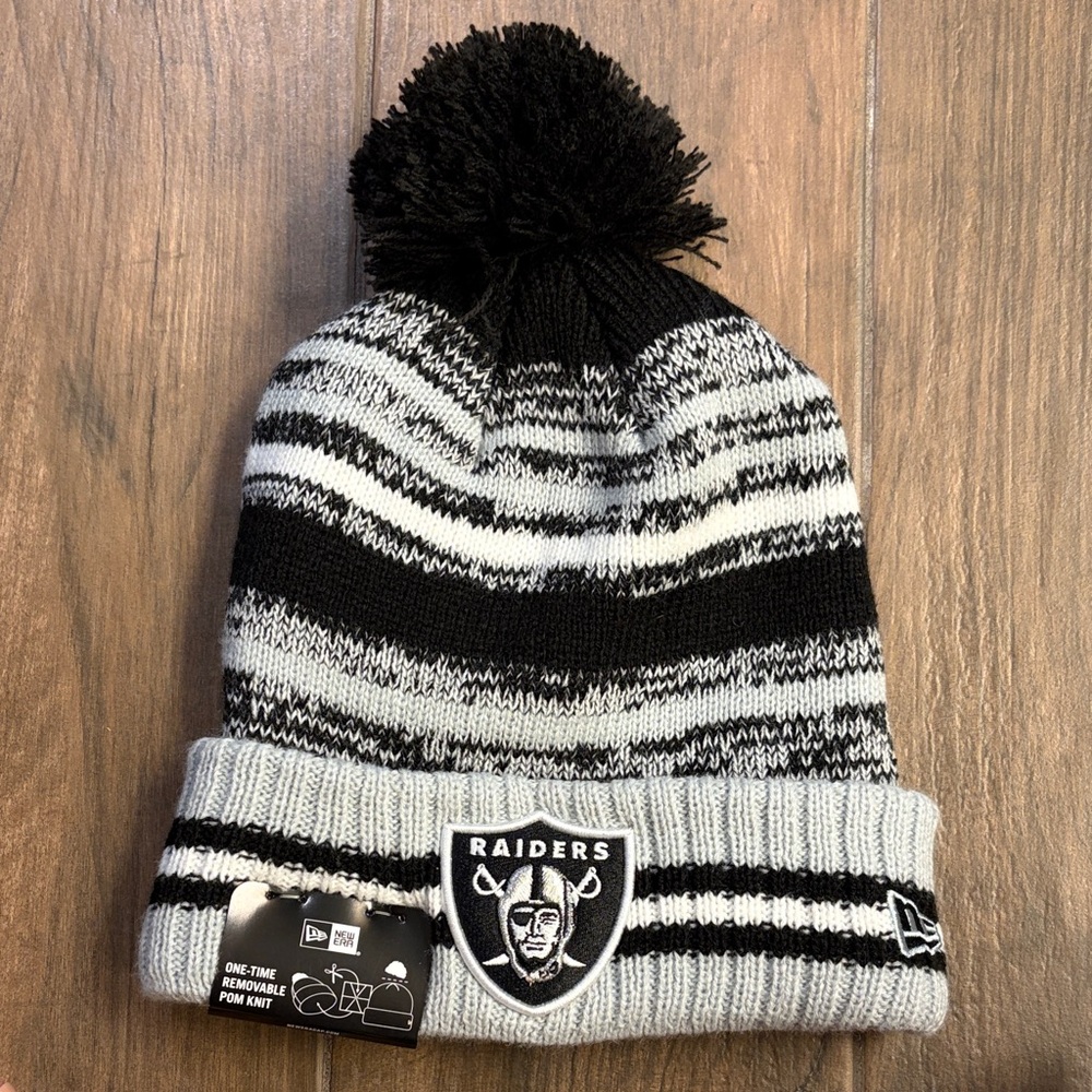 Brand New with Tag. New Era Black and Gray Striped Raiders Pom Pom Beanie.